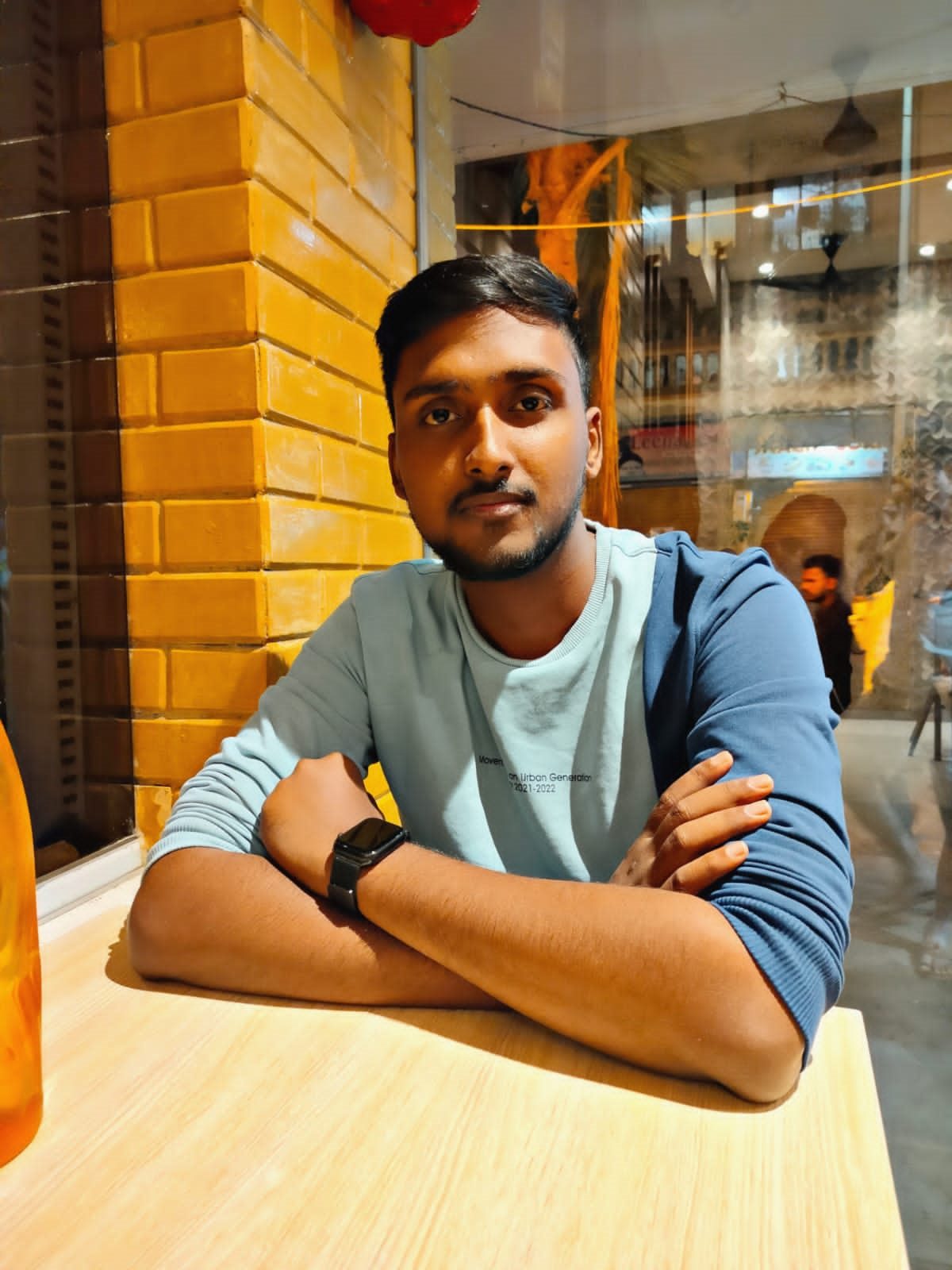 Vishwas Jha at a cafe table, arms folded, looking at the camera