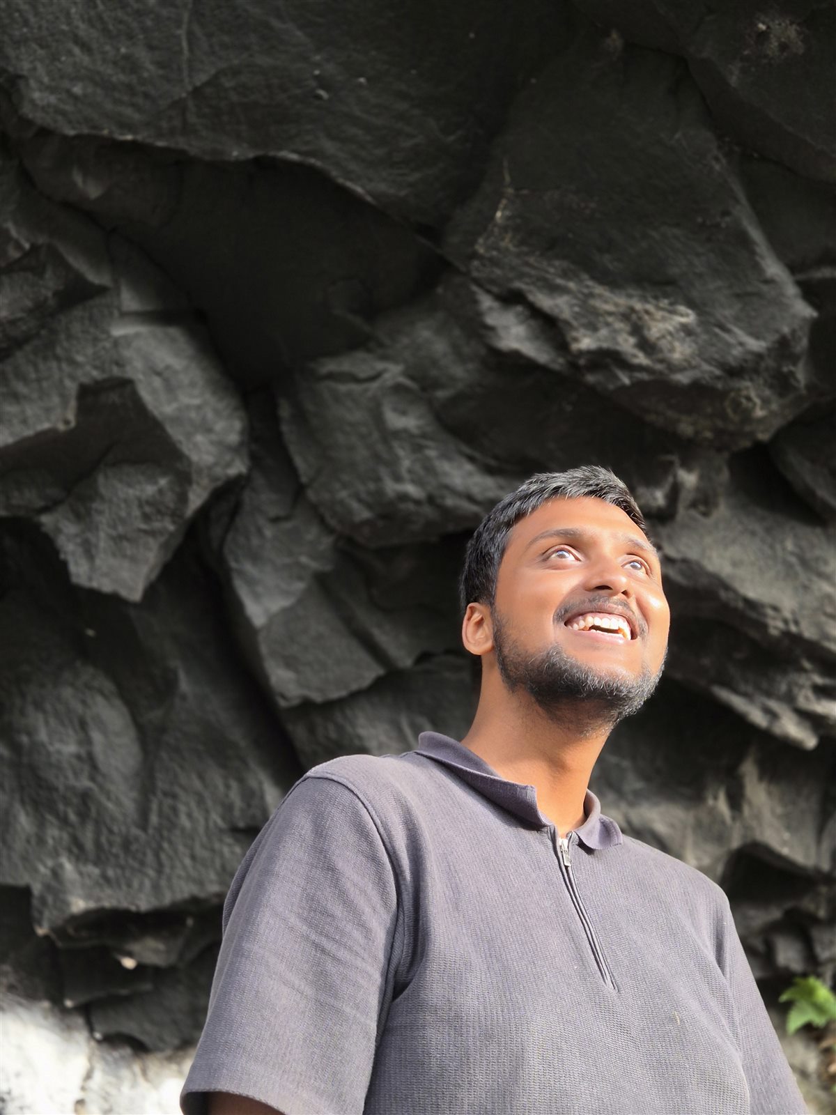 Vishwas Jha laughing, against a dark rock face